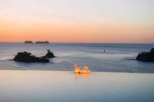 a person sitting in the water with a fire at Casa Chameleon Hotel Las Catalinas - Adults Only in Playa Flamingo