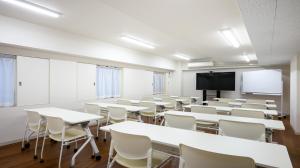 an empty classroom with tables and chairs and a screen at Quintessa Hotel Akita in Akita
