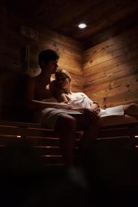 a man and a woman sitting on a bed at Hotel Wieser in Vipiteno