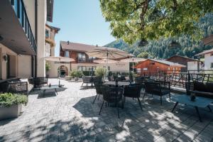 a patio with tables and chairs with mountains in the background at Hotel Wieser in Vipiteno