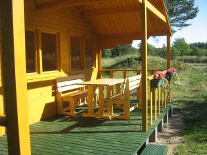 a wooden porch with a table and benches on it at Jaunveiti in Bernāti +7 photos