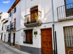 a white building with a wooden door and a balcony at Alojamiento Rural Ciudad Monumental in Baeza
