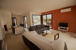 a living room with a couch and a tv at Villa au calme avec piscine privée - Lac de Jouarres in Olonzac