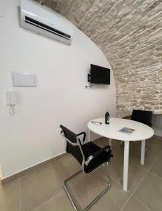 a white table and chairs in a room with a brick wall at Casa-Torre Normanna in Bitonto