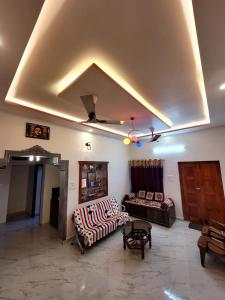 a living room with two couches and a ceiling at Deepa HomeStay in Dharmastala