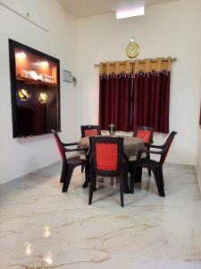 a dining room with a table and chairs and a clock at Deepa HomeStay in Dharmastala