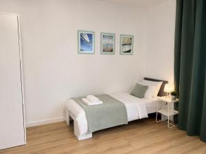 a white bedroom with a bed and a table at Apartamenty Przy Forcie in Kłodzko
