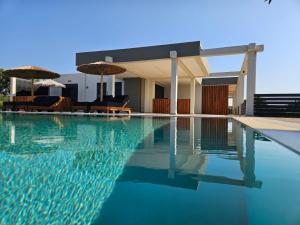 ein Swimmingpool mit Liegestühlen und Sonnenschirmen neben einem Haus in der Unterkunft Mat Suites in Lachania