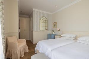 a white bedroom with two beds and a chair at Despotiko Hotel in Mikonos