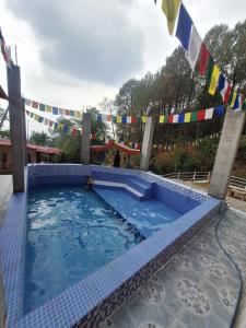 a pool at a resort with flags in the background at TATHASTU RETREAT BiR -TRB in Bīr