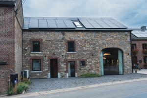 a brick building with solar panels on it at Stone Barn Menil Sauna & Nordic Bath in Ardennes in Hotton