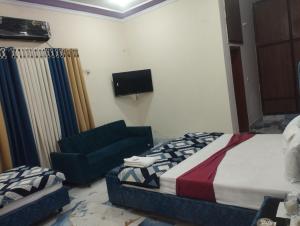 a bedroom with a bed and a couch and a tv at Hotel Multan Avenue Multan in Multan +31 photos