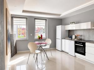 a kitchen with white cabinets and a table and chairs at Kwartał Dominikański in Kamień Pomorski