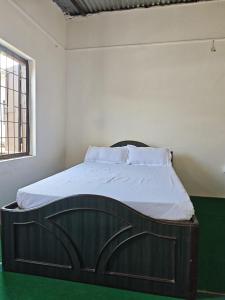 a bedroom with a large wooden bed with white sheets at Gatlang Backpackers in Trisūli Bāzār