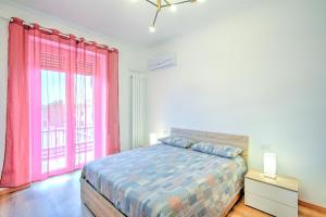 a bedroom with a bed and a window with pink curtains at La casetta al mercato in Civitavecchia