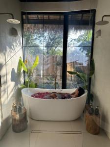 a bath tub with a person in it in front of a window at Alma Villas in Paliton