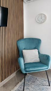 a blue chair with a pillow and a clock on a wall at Apartment BayView in Donji Morinj