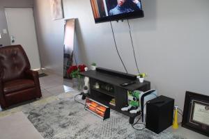 a living room with a tv on a wall and a couch at Penthouse in Bloemfontein