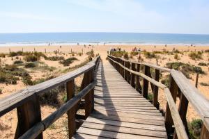 ein Holzsteg, der zum Strand führt in der Unterkunft Hostal Manuela in Punta Umbría