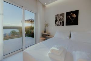 a bedroom with a white bed and a sliding glass door at Lefka Apartment in Vivari