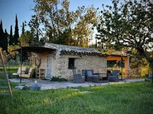 a stone house with chairs and a patio at Cabanon bucolique face au Luberon in Lourmarin