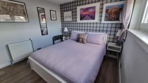 a small bedroom with a bed with purple sheets at Innisfail Edi - double room with private bathroom in Edinburgh