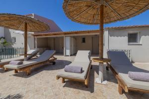 a patio with chaise lounges and an umbrella at Cavaliere Seafront House - Klio in Sami