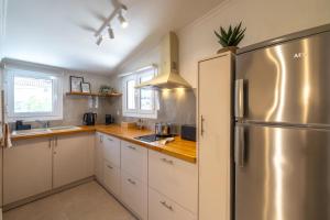 a kitchen with white cabinets and a stainless steel refrigerator at Cavaliere Seafront House - Klio in Sami
