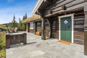 a wooden cabin with a green door on a patio at Orreleiken in Åmot