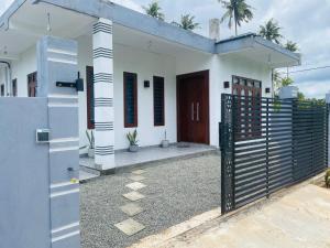 a white house with a gate and a fence at Elysian Riverside in Weligama