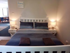 a bedroom with a large bed with two tables and two lamps at Beach & Forest Stay in Port Arthur