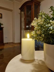 a candle sitting on a table next to a vase of flowers at COZY PANORAMA Flat in Alba Iulia