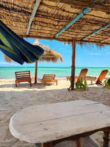 a beach with benches and a hammock and the ocean at Chez Émile in Anakao