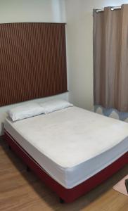 a bed in a room with a white mattress at Ótima localização in Imperatriz