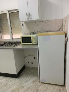 a kitchen with a counter with a microwave and a refrigerator at Hostel MJ ,Sidi kbir in Zarzis