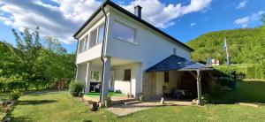 a white house with a hill in the background at Apartman Anna & Kamp Elza in Bihać