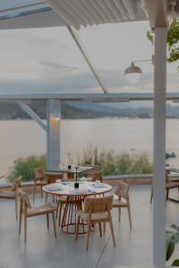 a patio with tables and chairs and a view of the ocean at Lefka Apartment in Vivari +25 photos