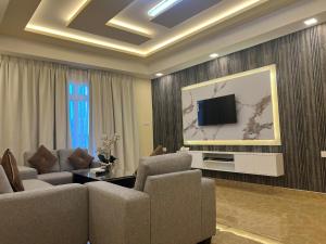 a living room with couches and a flat screen tv at Amber Tower in Al Ghurayfah