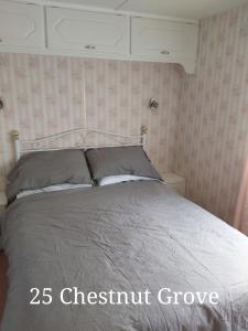 a bedroom with a bed with a gray comforter at 25 Chestnut Grove in Kirkcolm
