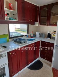 a kitchen with red cabinets and a sink at 25 Chestnut Grove in Kirkcolm