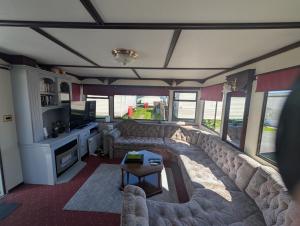 a living room with a large couch and a table at 25 Chestnut Grove in Kirkcolm