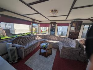 a living room with a large couch and a table at 25 Chestnut Grove in Kirkcolm +1 photo