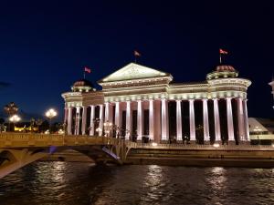 a building with columns on a bridge at night at FORUM Square in Skopje