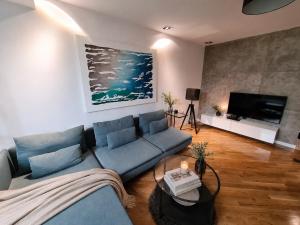a living room with a blue couch and a tv at FORUM Square in Skopje