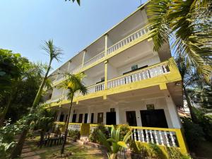 a yellow building with palm trees in front of it at Durga Beach Resort in Parxem