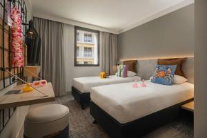 a hotel room with two beds and a table at Moxy Nice in Nice
