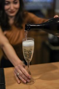 a woman pouring champagne into a glass on a table at Solea Family Hotel & Restaurant l Free Parking in Ravda