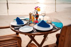 a table with blue napkins and plates on the beach at fehivilla resistance in Dhangethi