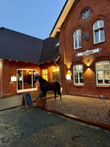 a horse standing in front of a brick building at Gaststätte Bongsiel 'Dat Swarte Peerd' in Ockholm
