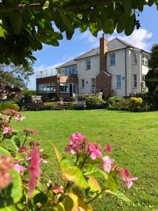 a large house with pink flowers in the yard at Elmsleigh in Marhamchurch